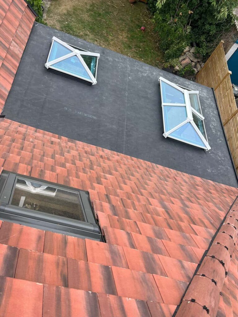 This is a photo taken from the roof ridge looking down a tiled pitched roof on to a flat roof. Works carried out by LJ Roofing Walcot
